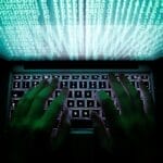 Hands typing on laptop keyboard with binary code, symbolizing cybersecurity and hacking. | Cyberinsure.sg